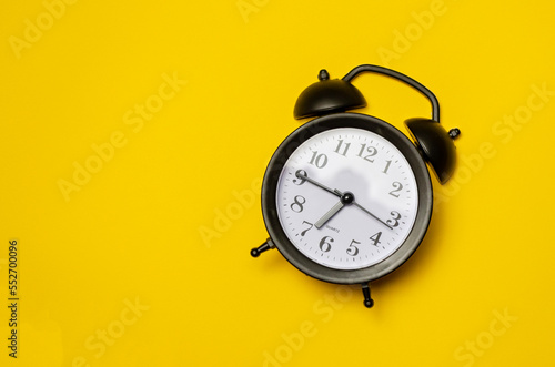 black vintage alarm clock on yellow colour background