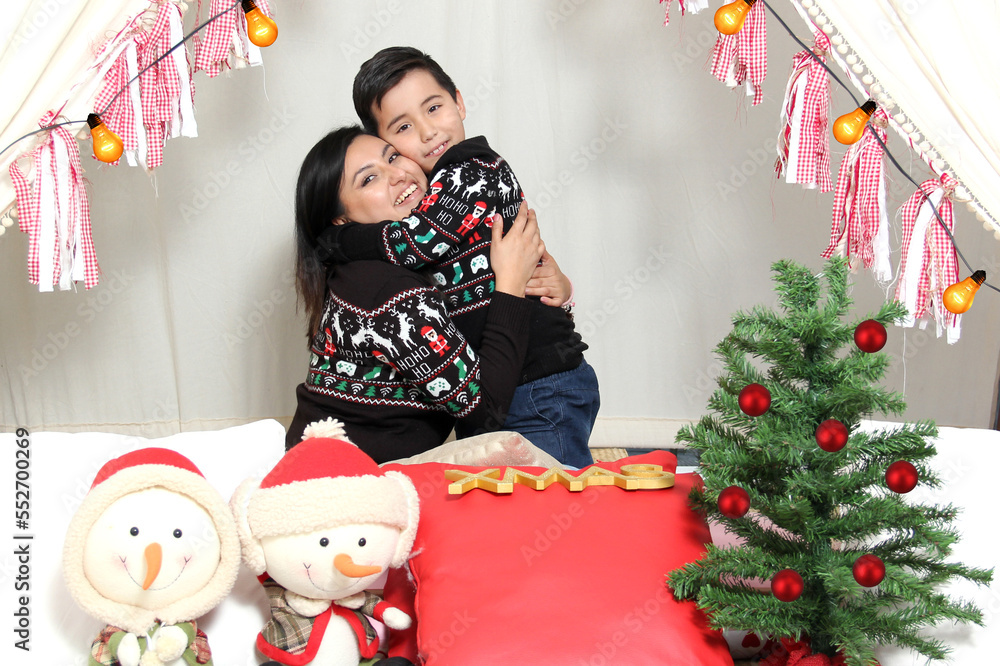 Mom and son celebrate Christmas under a teepee dressed in ugly sweaters with lights and Christmas decorations show their love and share quality time Mom and son celebrate Christmas under a teepee dressed in ugly sweaters with lights and Christmas decorations show their love and share quality time