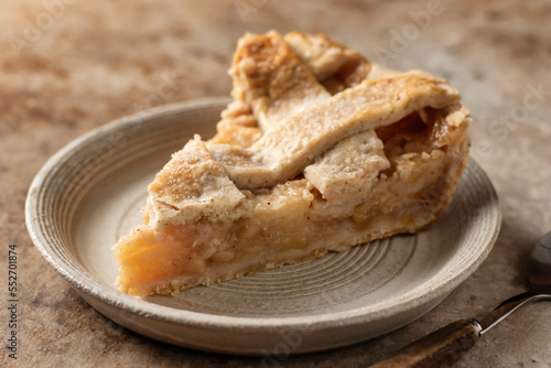 Slice of traditional apple pie on ceramic plate on brown textured background, menu