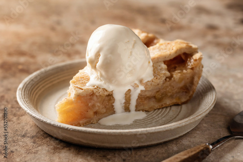 Slice of traditional apple pie with ice cream on brown textured background, menu