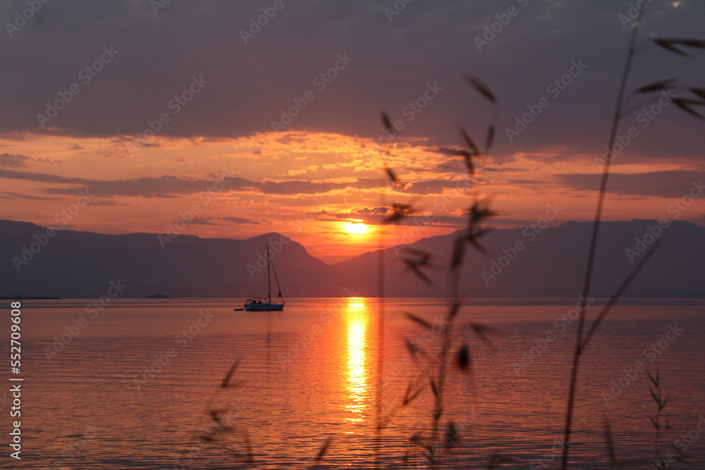 Scenic sunset and a lonely sailboat at the coast of Trogir