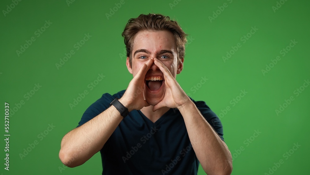 Portrait of happy young man 20s smiling scream and shout calling inviting with hands at mouth say hey you isolated on solid green screen background Portrait of happy young man 20s smiling scream and shout calling inviting with hands at mouth say hey you isolated on solid green screen background