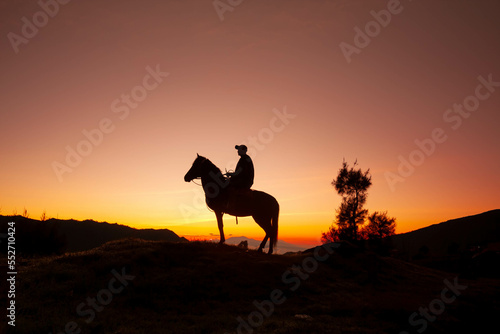 A silhouette of a horsemen and his horse standing on the sand dune with foggy   misty morning background at Bromo-Tengger-Semeru National Park  Indonesia