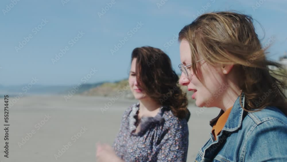Two women sitting on a beach talking and thinking. Medium Close Up with a rack focus between the two women. Two women sitting on a beach talking and thinking. Medium Close Up with a rack focus between the two women.