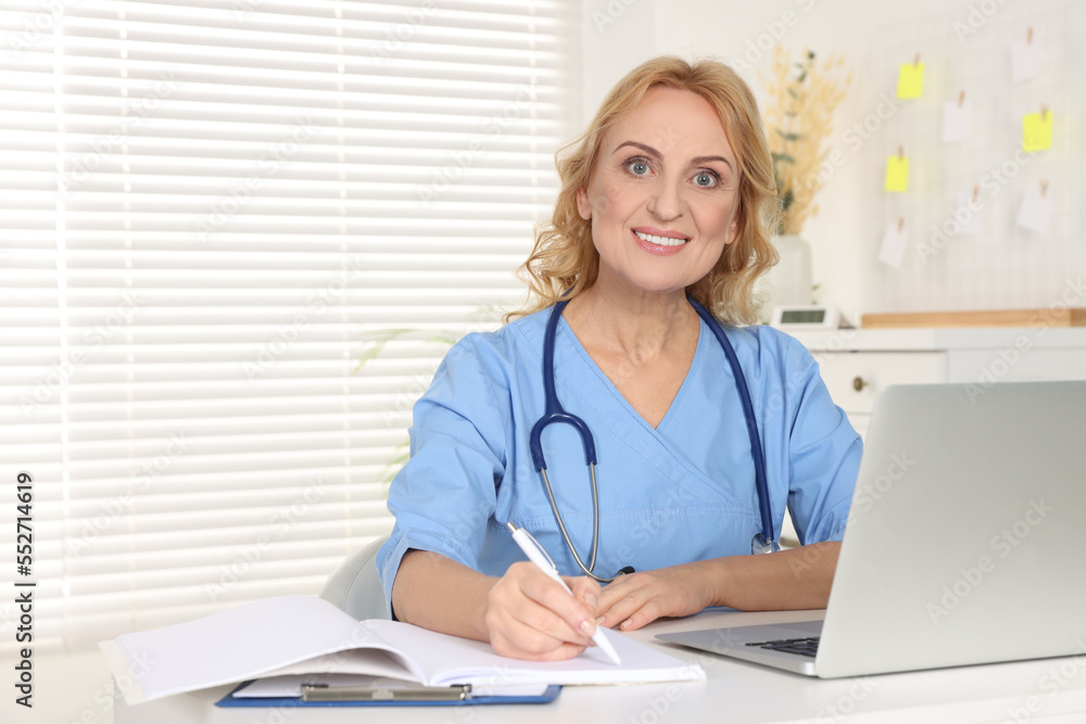 Portrait of doctor with laptop at workplace in clinic. Online medicine concept Portrait of doctor with laptop at workplace in clinic. Online medicine concept