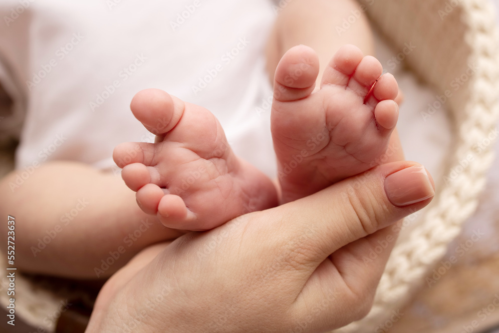 Children's foot in the hands of mother, father, parents. Feet of a tiny newborn close up. Little baby legs. Mom and her child. Happy family concept. Beautiful concept image of motherhood stock photo. Children's foot in the hands of mother, father, parents. Feet of a tiny newborn close up. Little baby legs. Mom and her child. Happy family concept. Beautiful concept image of motherhood stock photo.