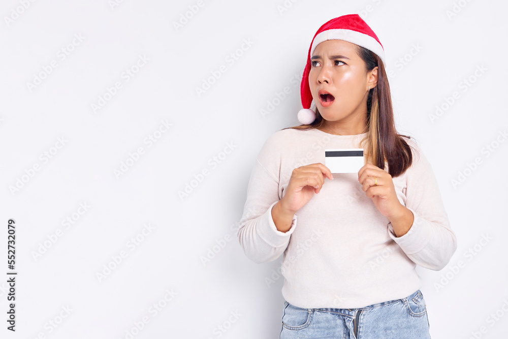 Cheerful and excited young Asian woman in a Christmas hat showing a blank white credit card at camera isolated on white background Cheerful and excited young Asian woman in a Christmas hat showing a blank white credit card at camera isolated on white background