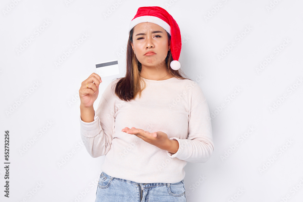 pensive young Asian woman in a Christmas hat showing a blank white credit card at camera isolated on white background pensive young Asian woman in a Christmas hat showing a blank white credit card at camera isolated on white background