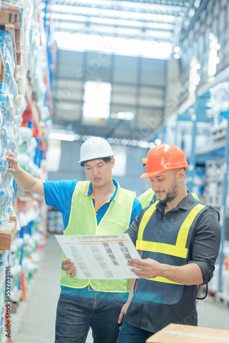 Warehouse workers in helmets checking goods and supplies on shelves with goods background in warehouse worker packing in a large warehouse in a large warehouse. Logistics industry concept..