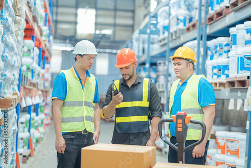 Warehouse workers in helmets checking goods and supplies on shelves with goods background in warehouse worker packing in a large warehouse in a large warehouse. Logistics industry concept..