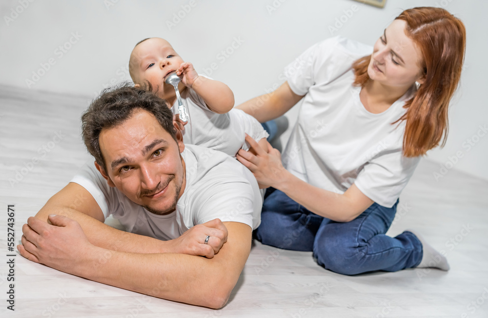 family in the studio or at home crawling on the floor with a baby. mom, dad, son play together family in the studio or at home crawling on the floor with a baby. mom, dad, son play together
