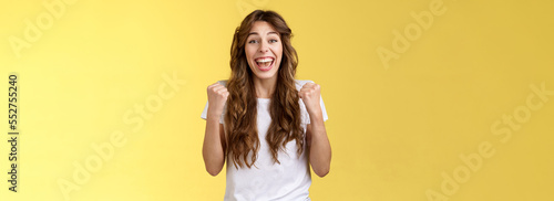 Yes finally success. Cheerful enthusiastic happy girl pump fists lift hands victory joy celebration gesture smiling broadly relieved winning lottery amused stand yellow background triumphing
