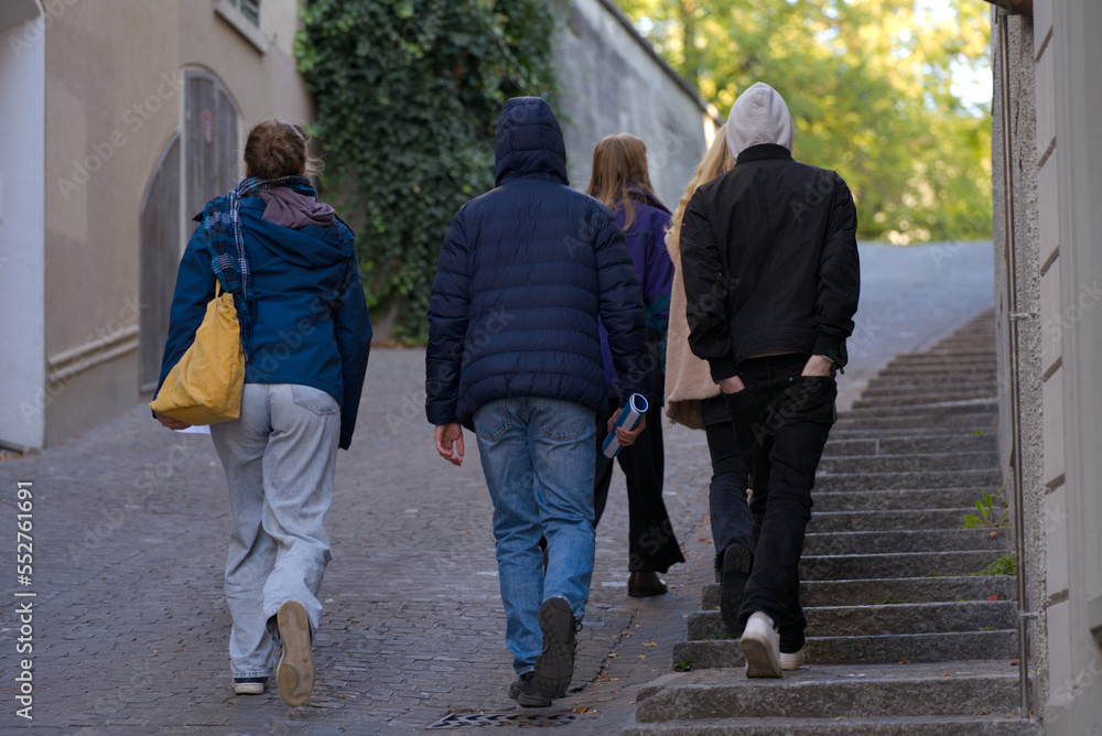 Group of young people walking up a hill to famous public park Lindenhof at the old town of Zürich on a sunny late summer morning. Photo taken September 22nd, 2022, Zurich, Switzerland.