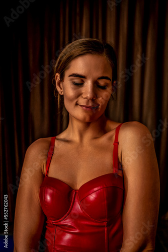 Party girl portrait. Young woman in red corset and black leather pants. Sexy seductive brunette in red and black costume. Role play. Celebration and party. Having fun.