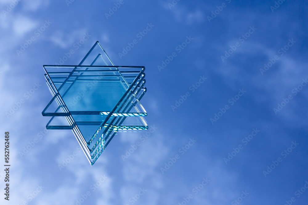 A clear glass placed on a mirror reflects the Star of David, a hexagram formed by overlapping two equilateral triangles in an upside-down manner. Known as the national symbol of the nations of Israel, A clear glass placed on a mirror reflects the Star of David, a hexagram formed by overlapping two equilateral triangles in an upside-down manner. Known as the national symbol of the nations of Israel,