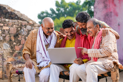 Bild auf Leinwand Indian villagers setting at in front of home and using laptop.
