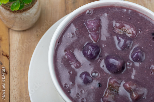 Ginataang Ube bilo bilo is a sweet coconut-based dessert soup with tapioca, chewy rice balls, and a variety of fruits and sweet potato photo