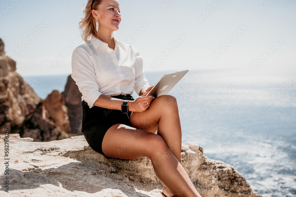 Digital nomad, Business woman working on tablet pc pad computer by the sea. Pretty lady with tablet pc on the sea, makes a business transaction online from distance. Freelance, remote work on vacation