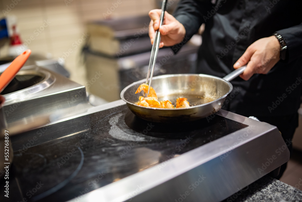 man chef cooking tasty shrimp in frying pan on kitchen man chef cooking tasty shrimp in frying pan on kitchen