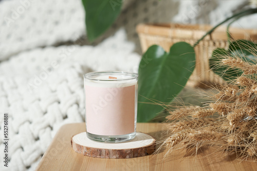 soy wax candle in a glass on bedtable with dry whey ears decor. home scents, aroma candles for cozy ambient house. photo