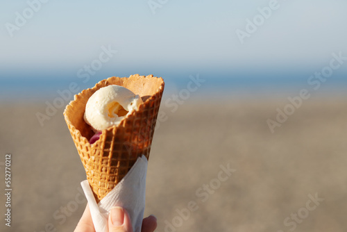 ice cream balls in a waffle cone in hand on the beach at sea