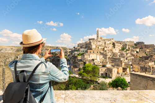 Young woman tourist makes a panorama photo of the ancient city of Matera on a sunny day, Italy.