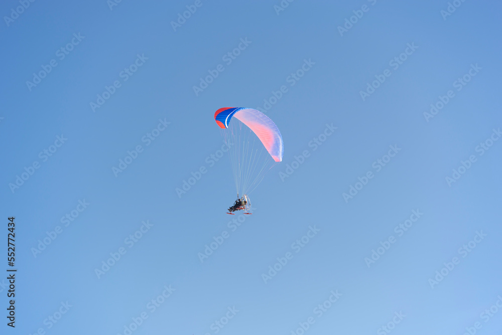 A paraglider with a sled in the blue sky. Winter fun. A paraglider with a sled in the blue sky. Winter fun.