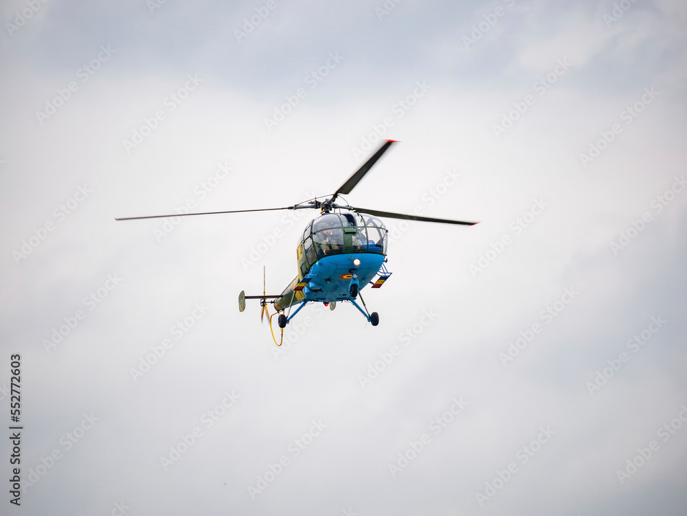 Fototapeta premium Light utility and trainer helicopter flying against a cloudy sky. Airshow demonstration.