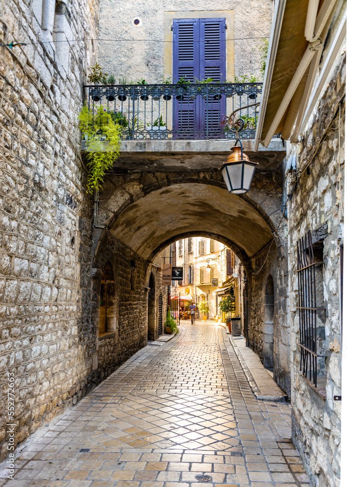 Narrow streets with arch passage under colorful historic houses at Rue de l’Eveche street in old town of medieval riviera resort of Vence in France