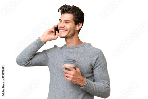 Young handsome caucasian man over isolated background holding coffee to take away and a mobile photo