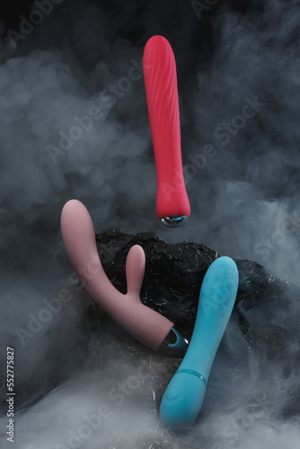 Silicone sex toys in puffs of smoke on a black background Sexual Clitoris Massager for Women Erotic toy for fun Sex gadget and masturbation device Place for text Sex shop concept Dildo Vibrators