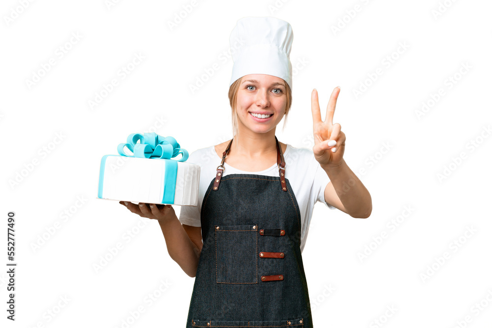 Young pastry blonde woman with a big cake over isolated chroma key background smiling and showing victory sign Young pastry blonde woman with a big cake over isolated chroma key background smiling and showing victory sign