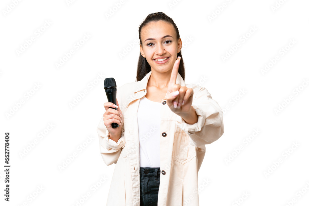 Young singer woman picking up a microphone over isolated chroma key background showing and lifting a finger