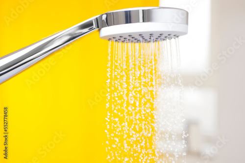Close-up of flowing water drops from a shower head in a bright bathroom