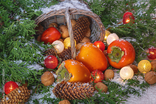 Christmas (New Year) composition with branches of coniferous trees, fruits, nuts, fir cones, luminous garland and gift basket
