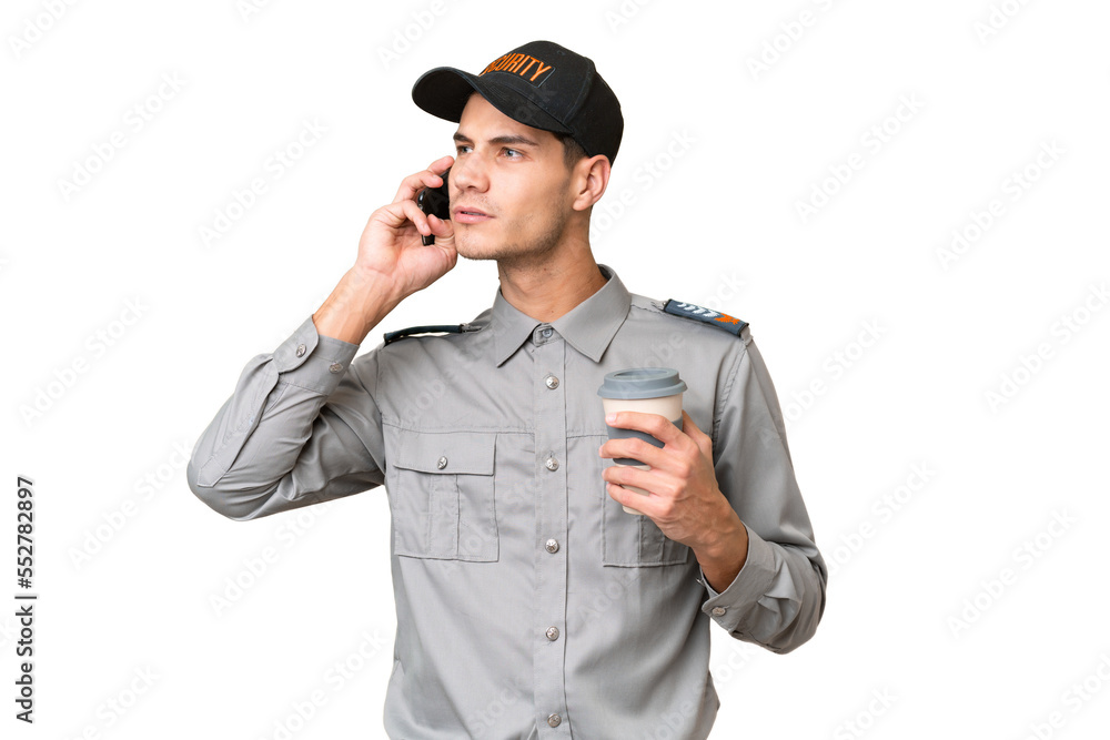 Young security man over isolated background holding coffee to take away and a mobile Young security man over isolated background holding coffee to take away and a mobile