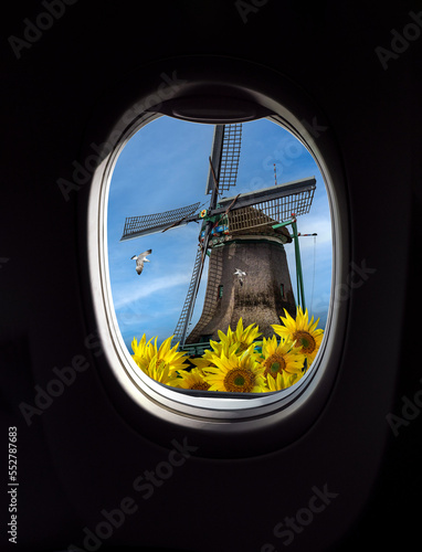 Landscape with old hollands windmill with sunflowers, view from porthole window of an airplane. Concept for travel agensy, airlines company or passengers airway transportation in Netherlands. photo