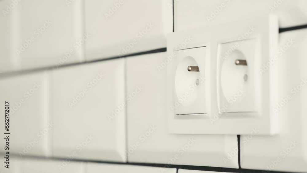 Human hand unplugs cable from socket with electricity connection. Safe voltage usage from energy network Human hand unplugs cable from socket with electricity connection. Safe voltage usage from energy network