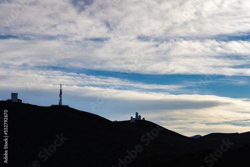 Silhouettes of a mountain and broadcasting antennas. Mountain landscape in winter. Snowy mountain in the background. Snowy mountain in the background.Tenerife, Canary Islands, Spain.