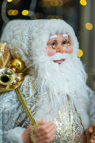Fototapeta Naklejka Na Ścianę i Meble -  Statuette of Santa Claus. Beautiful big doll of Santa Claus. Bokeh lights..