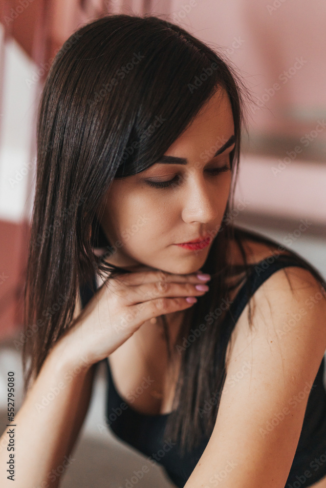a young beautiful girl with black long hair is sitting on the stairs. Beautiful young brunette in black pants and top posing on the landing a young beautiful girl with black long hair is sitting on the stairs. Beautiful young brunette in black pants and top posing on the landing
