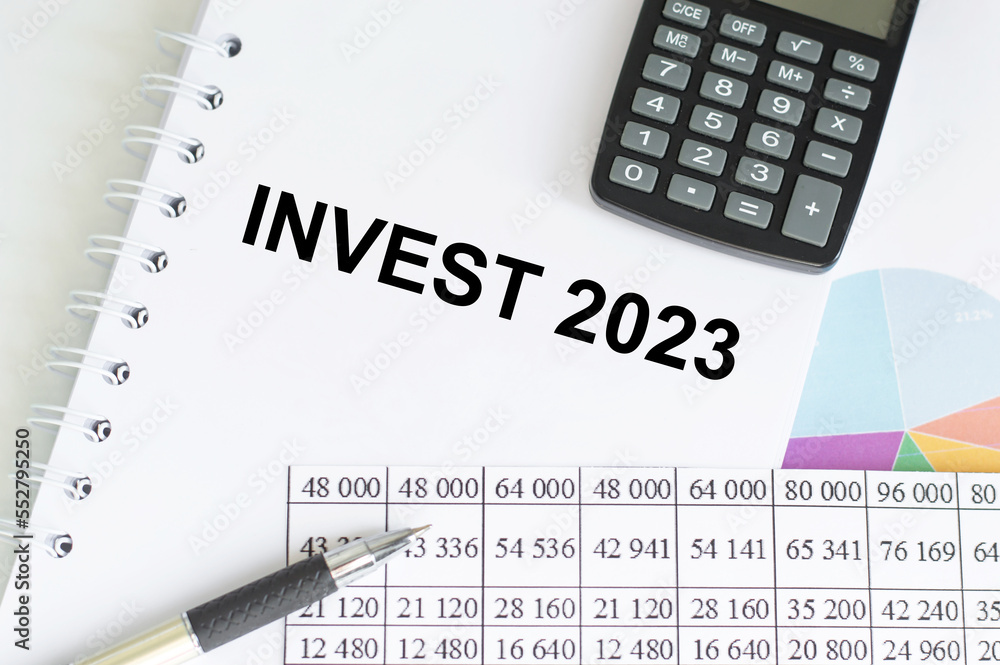 INVEST 2023 words on a small piece of paper next to a calculator. INVEST 2023 words on a small piece of paper next to a calculator.