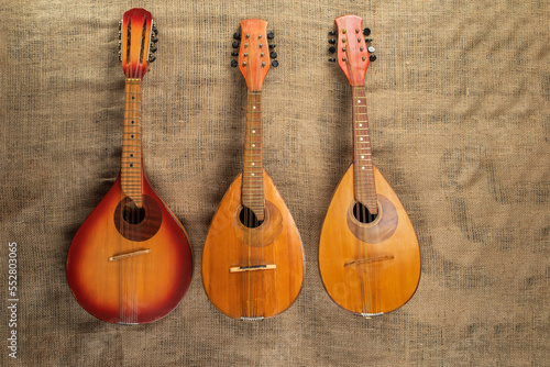 Three old mandolins on a background of rough burlap texture.