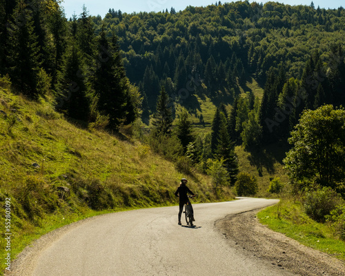 Girl with MTB in the middle of the road in the Romanian Mountains. Greet bike roads in the Bucegi Mountains. Mountain Biking in rural environment with fresh air and a lot of green. photo