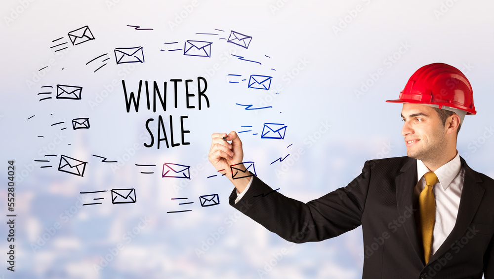Young businessman with helmet drawing sale sign Young businessman with helmet drawing sale sign