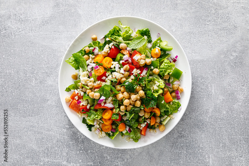 Tabbouleh salad. Tabouli salad with fresh parsley, onions, tomatoes, bulgur and chickpea. Healthy vegetarian food, mediterranean diet. Top view photo