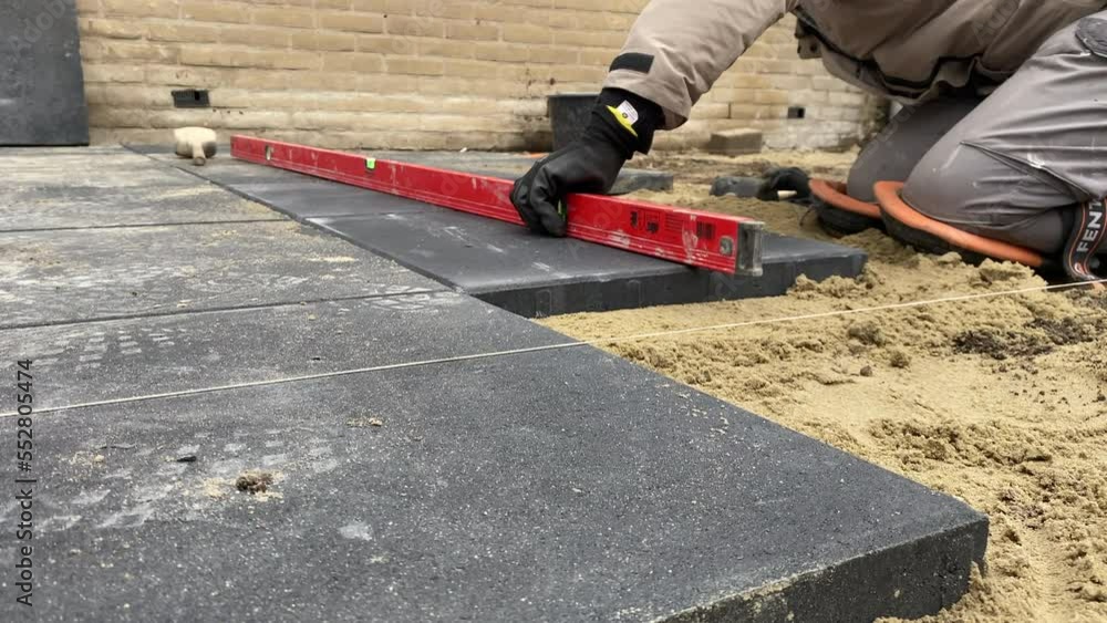 A worker laying paving slabs on the street 