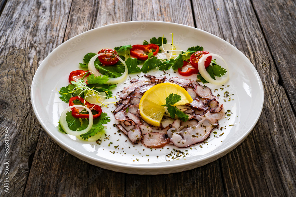 Octopus carpaccio with lemon and greens on wooden table
Octopus carpaccio with lemon and greens on wooden table
