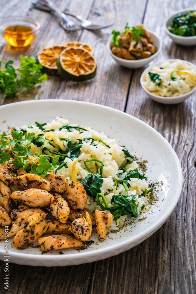 Fried chicken nuggets with white rice and spinach on wooden table
