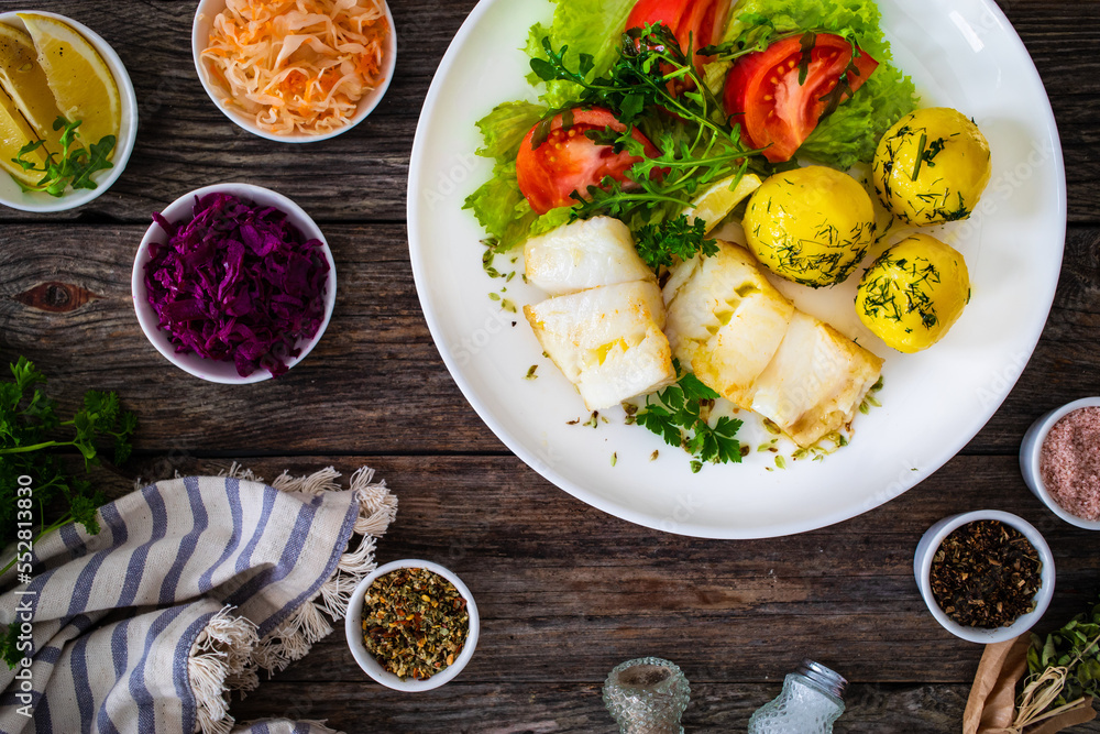 Fish dish - fried halibut with boiled potatoes and fresh vegetables on wooden table
Fish dish - fried halibut with boiled potatoes and fresh vegetables on wooden table